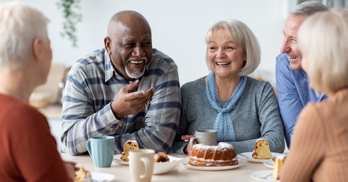 positive elderly people drinking tea with cake