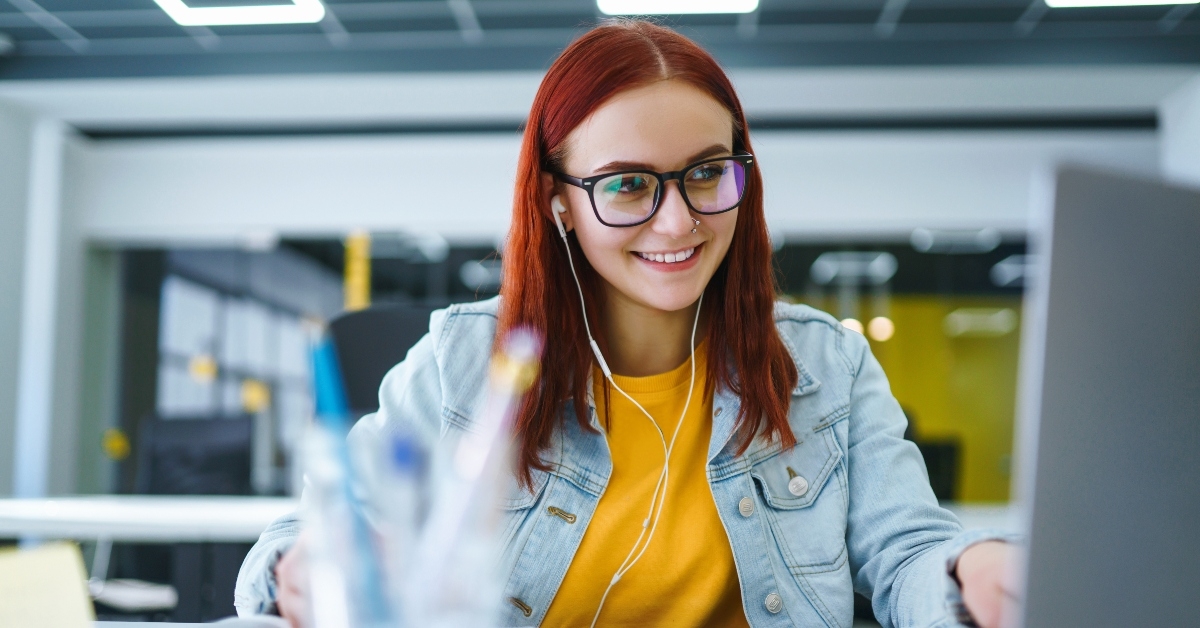 student at the computer listens music to earphones
