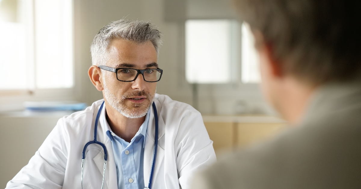male doctor in clinic talking to patient sitting across table