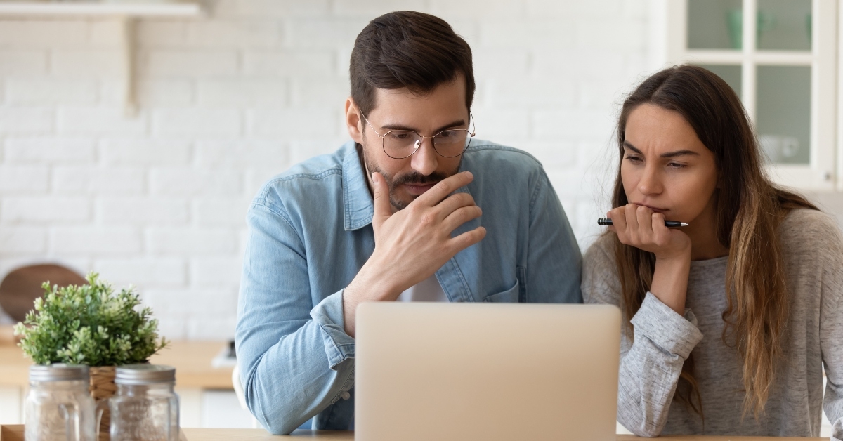 serious couple looking at laptop reading news