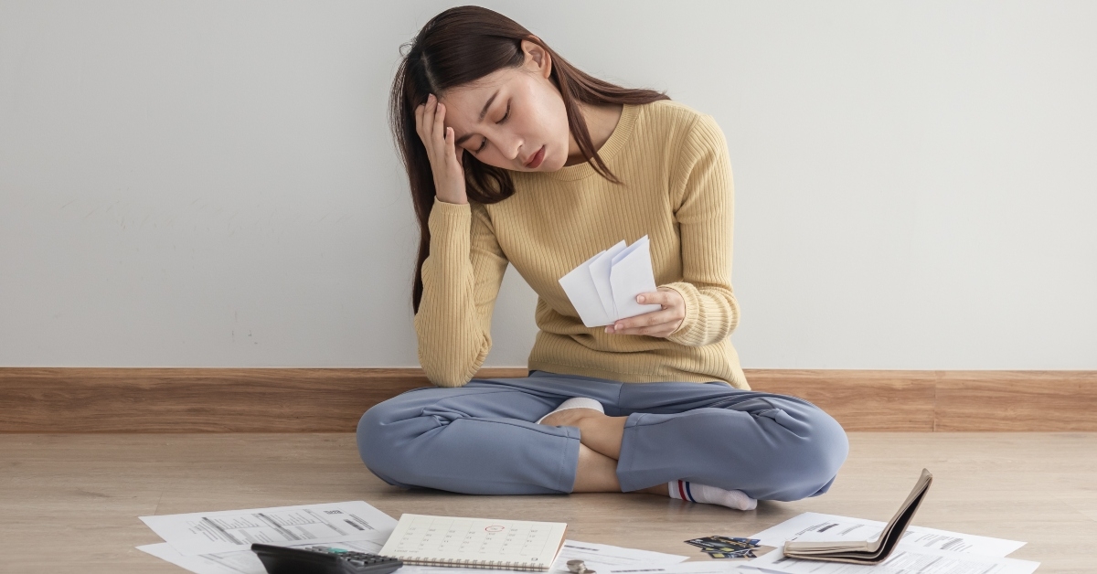 stressed female sitting on floor home calculating bills