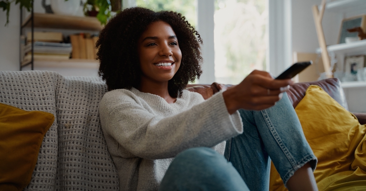 woman sitting on couch at home watching tv