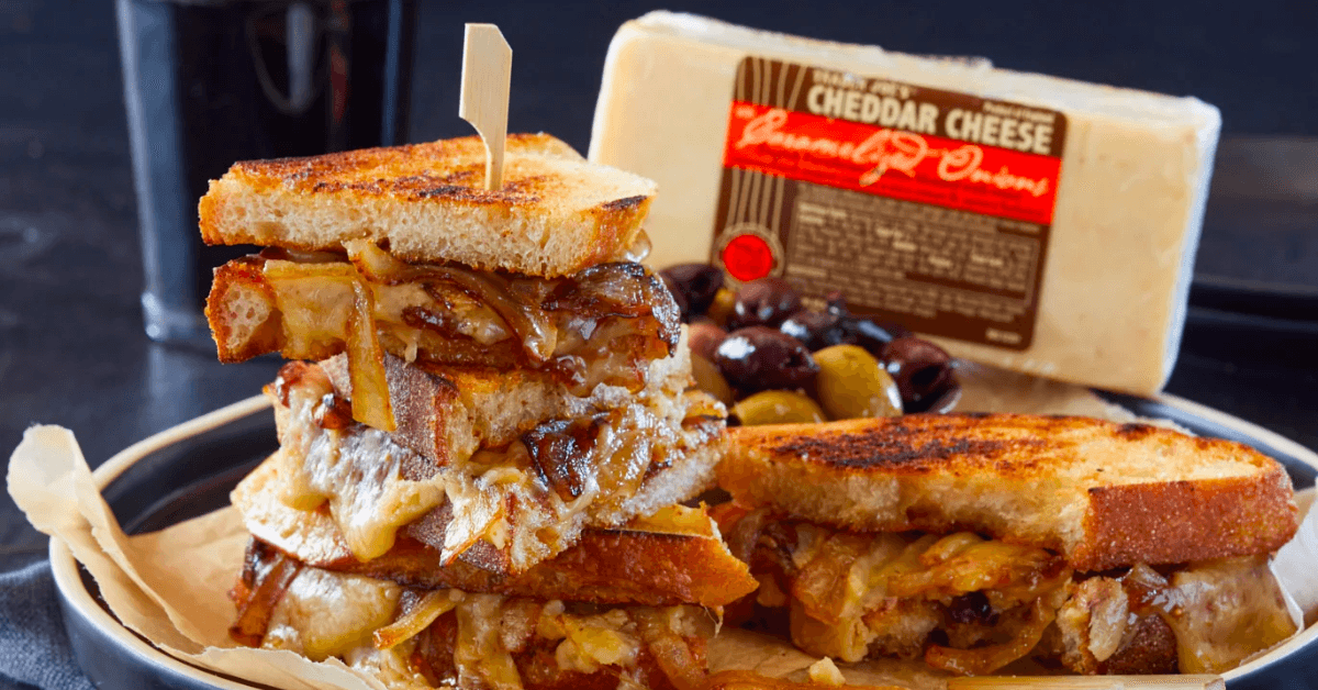 Grilled cheeses plate with caramelized onions and in the back a block of Trader Joe's Cheddar Cheese Caramelized Onions