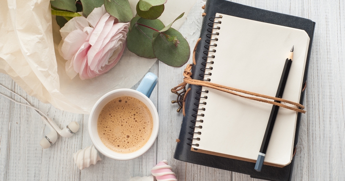 blank notebook bouquet cup of coffee earphones