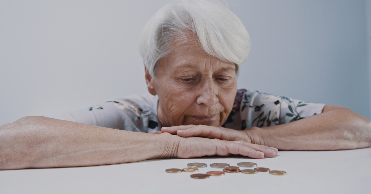 old gray haired woman looking in few coins left on the table