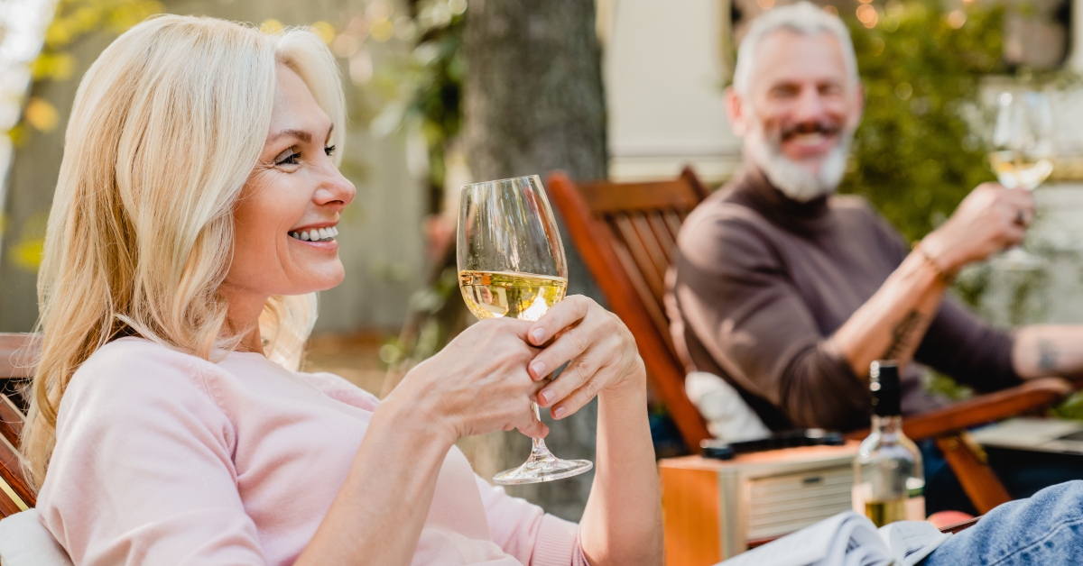 senior woman holding a glass of wine talking with her husband