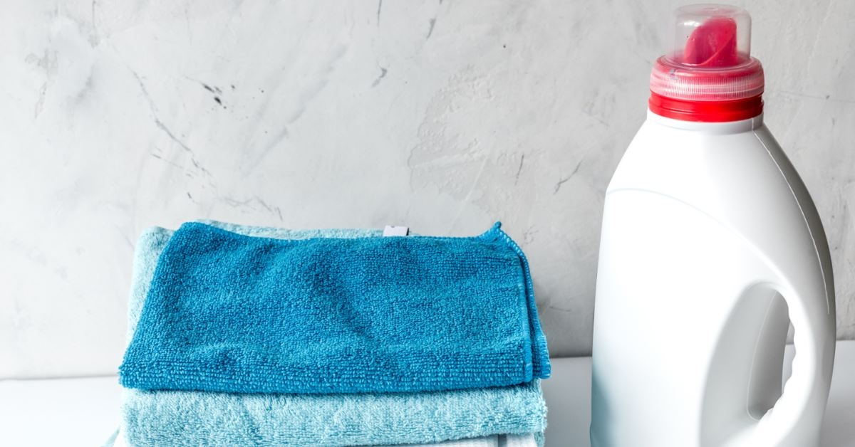 colorful towels besides cleaning detergent in white bottle in laundry room