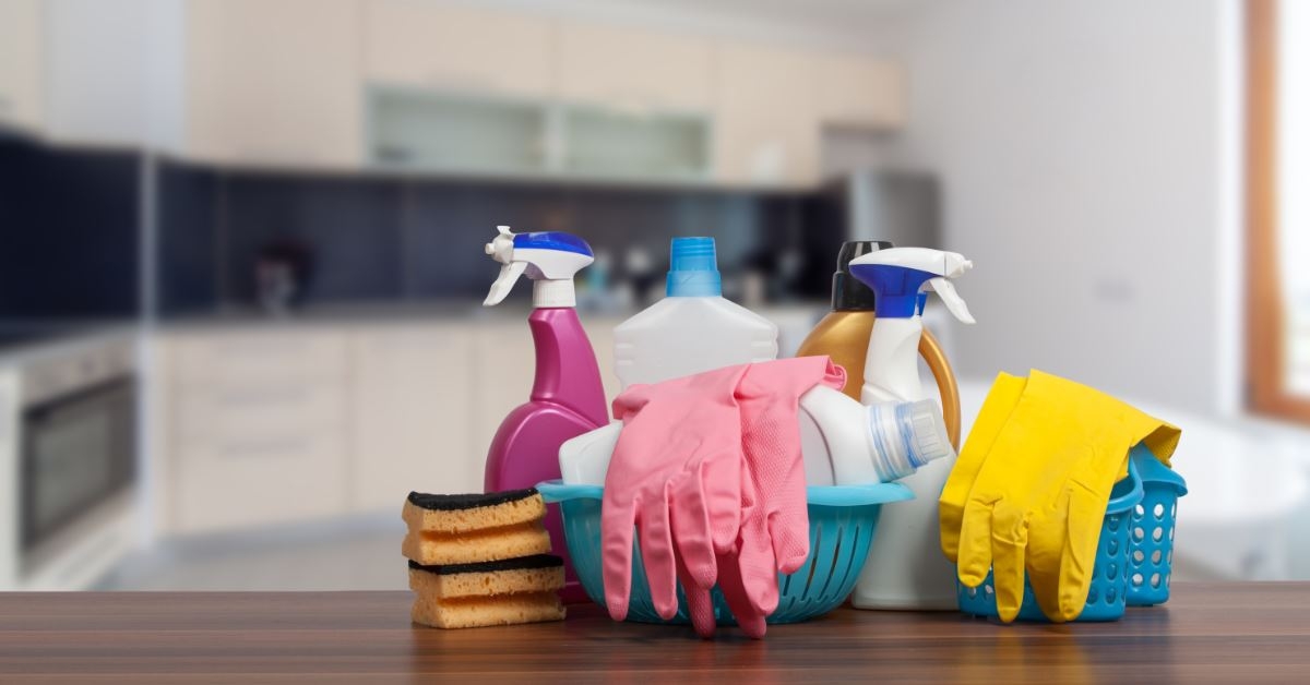 basket with home cleaning supplies in kitchen