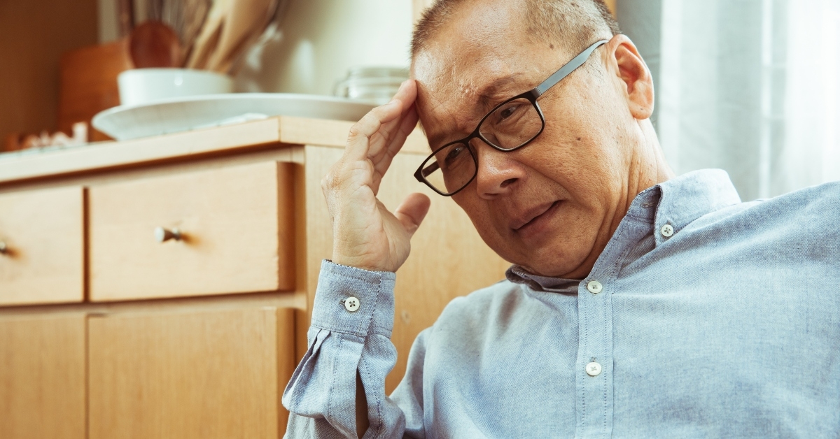 senior man sitting on sofa and having headache