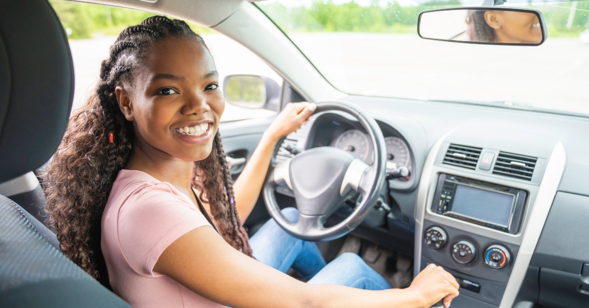 young black teenage driver seated in her new car