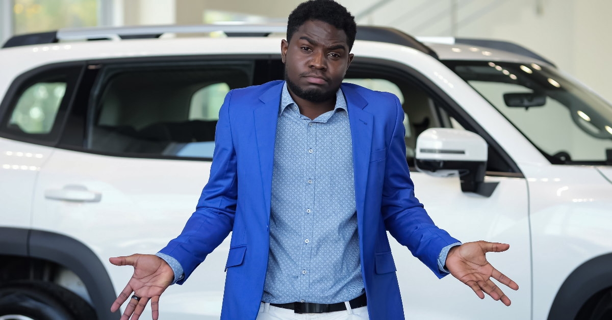 african american man standing in car showroom confused about which car to buy