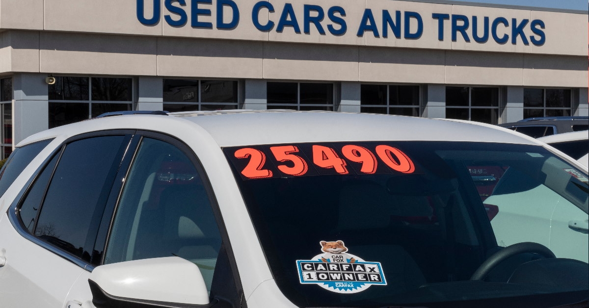 carfax sticker on pre owned car front window with used cars and trucks centre in background