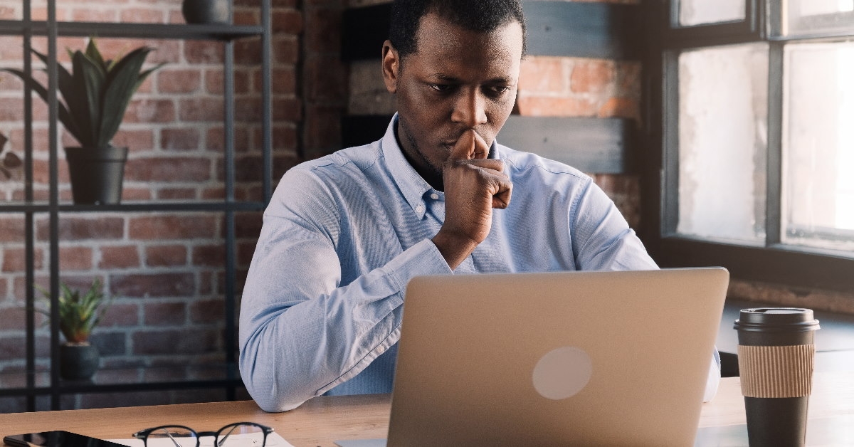 man focusing on laptop at work with coffee smartphone and glasses on table