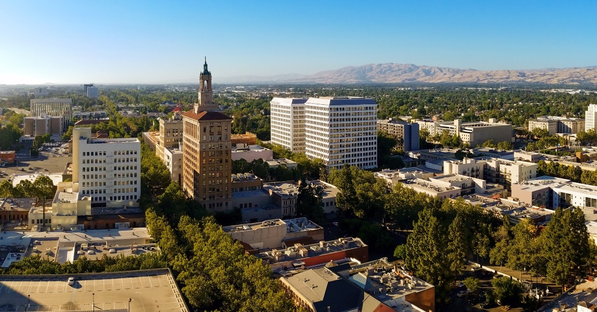 trees surrounding tall buildings with mountains in background at silicon valley in san jose