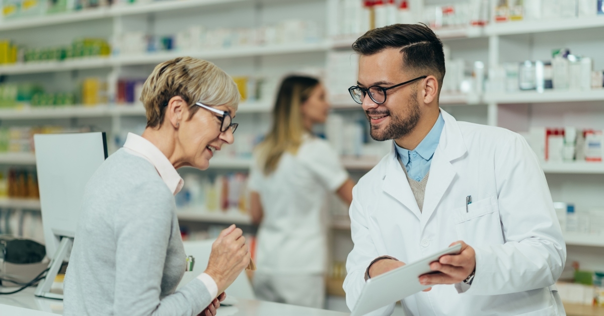 pharmacist giving prescription to senior female customer