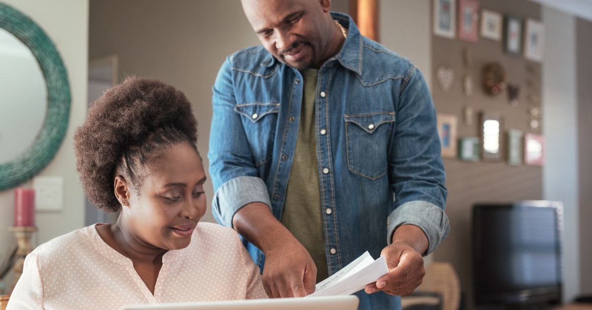african american couple with laptop at home discussing utility bills 
