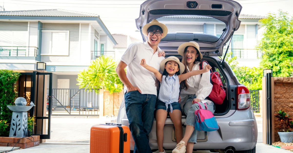 asian family posing for picture in suv trunk ready for vacation with suitcase in garage