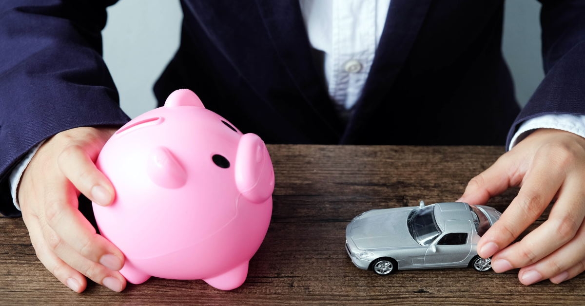businessman holding car and piggy bank on table showing saving money concept