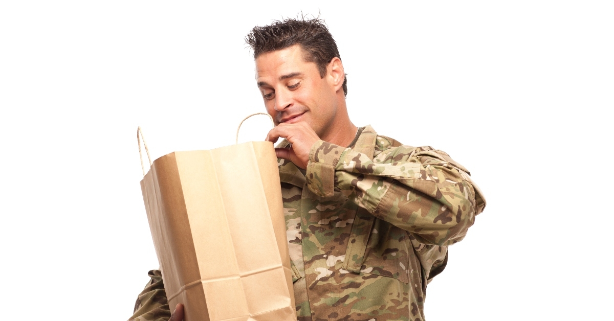 happy army soldier looking into his shopping bag