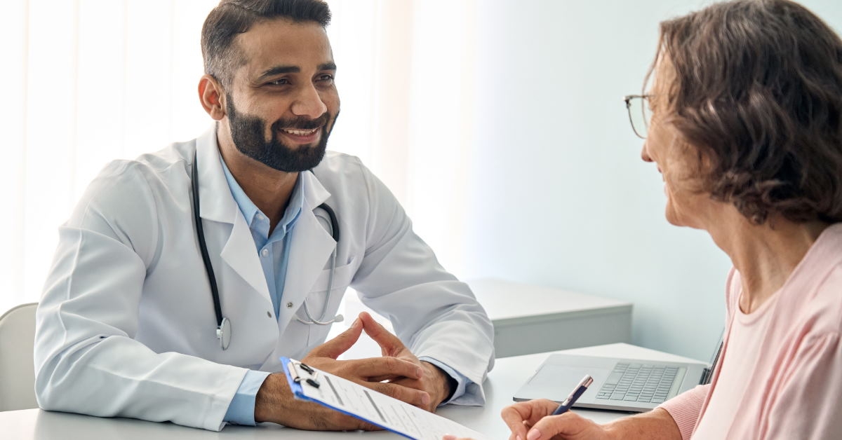 male doctor in discussion with senior female patient holding papers on clipboard