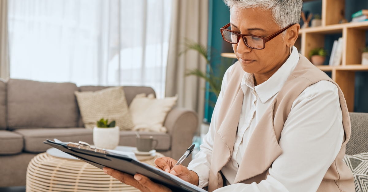 senior female psychologist sitting on couch checking client history on clipboard