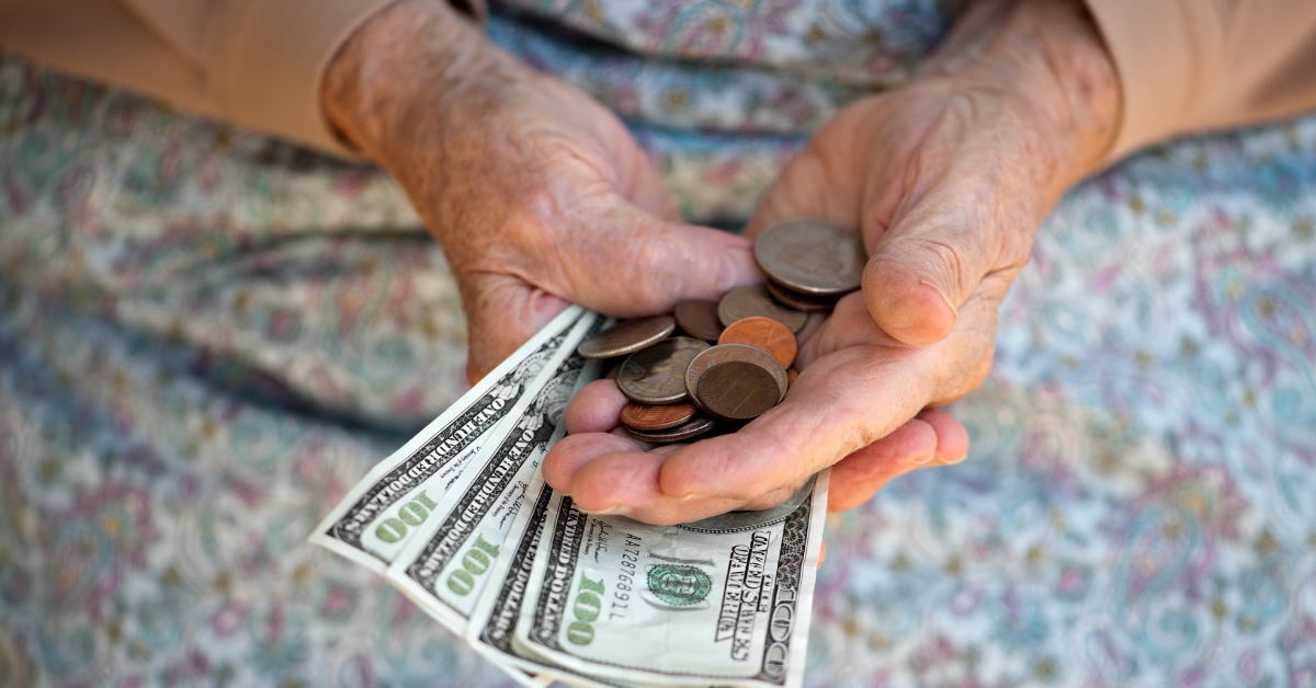 senior lady holding pennies and dollars in hand