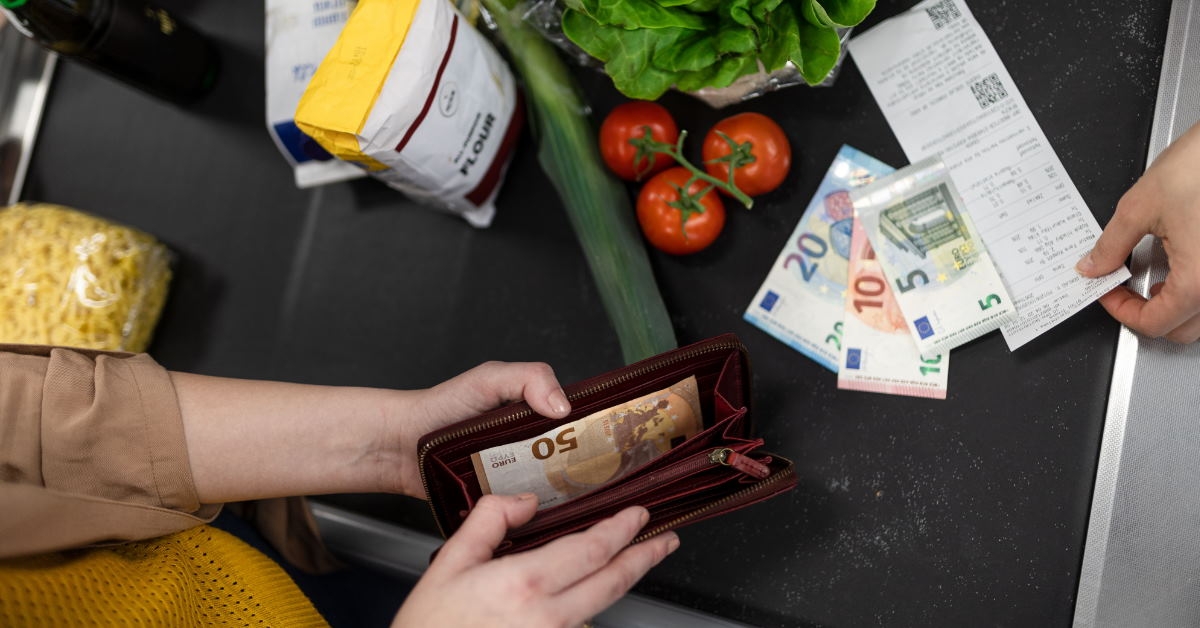woman paying money out of her wallet for purchasing grocery at store
