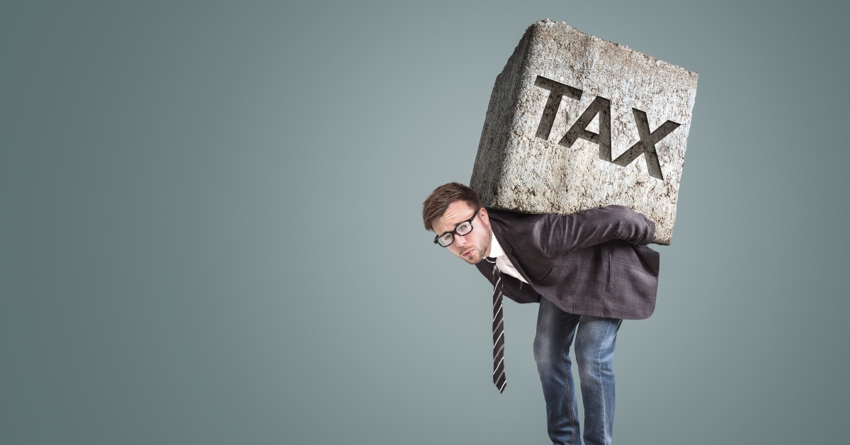 businessman carrying a heavy stone with the word TAX on it