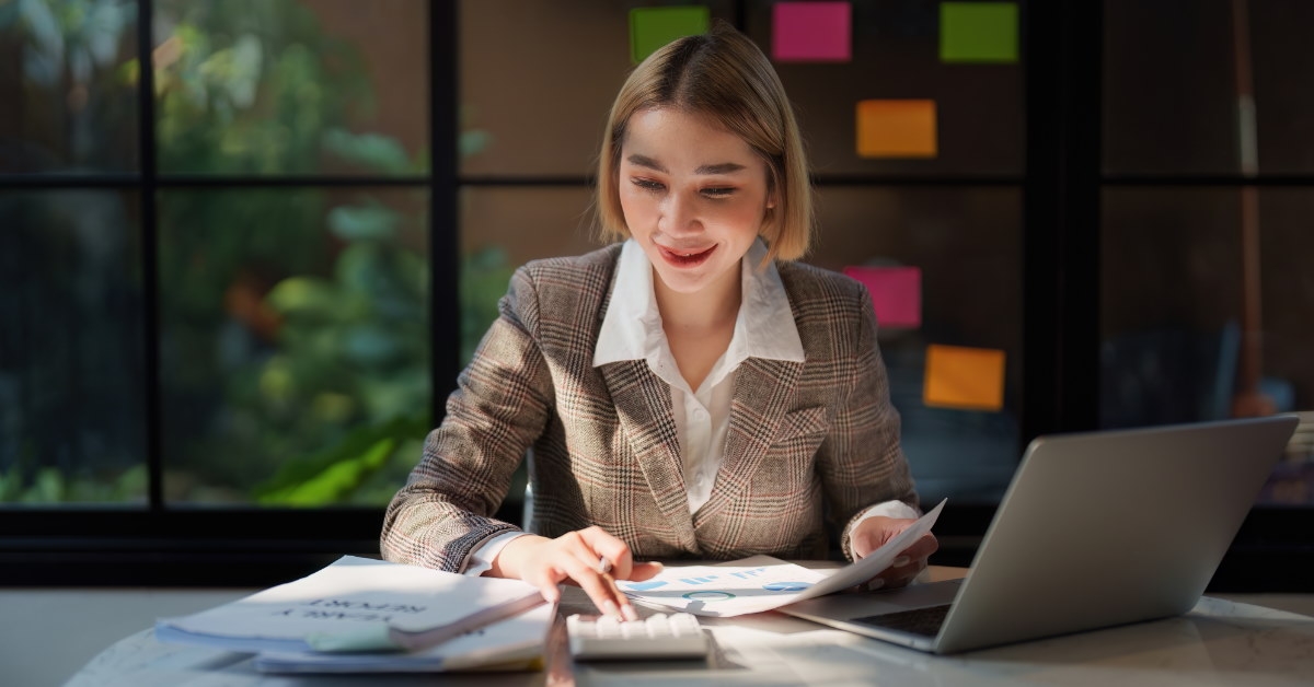 businesswoman in suit at office working using calculator and reviewing papers