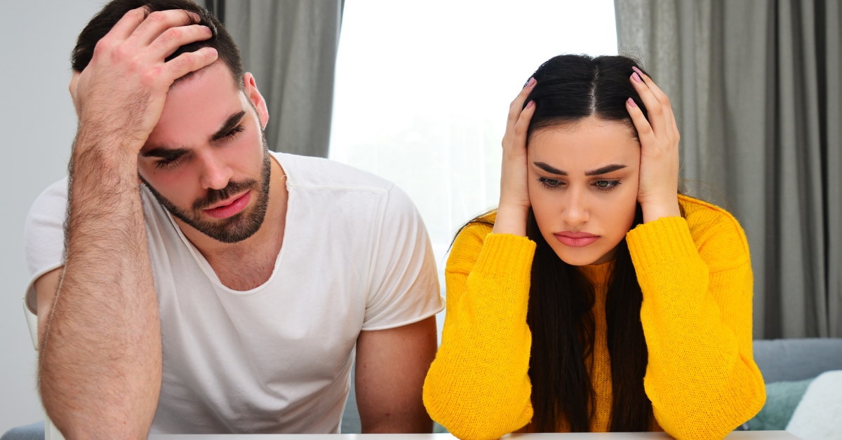 couple in depression due to taxes sitting at table with pennies