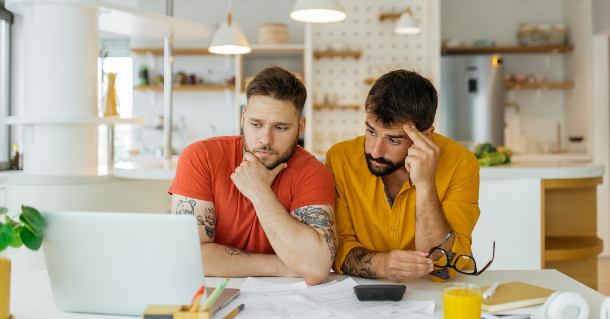 gay couple sitting at table stressing about bills 