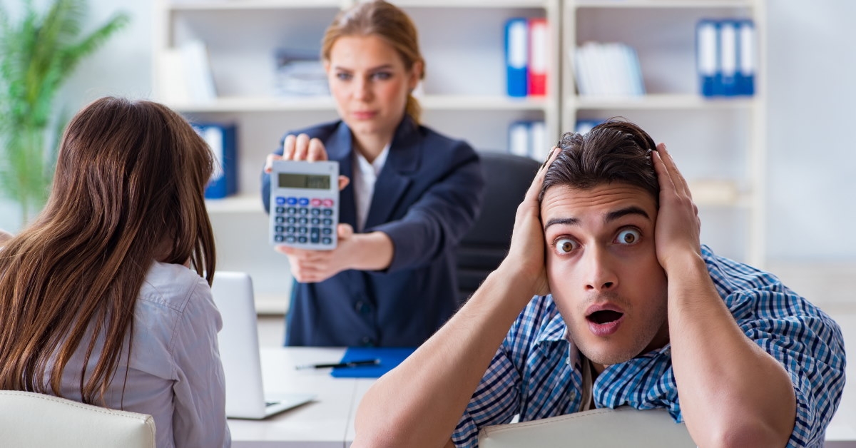 man in shock at high mortgage rate as female finance advisor shows him calculator 