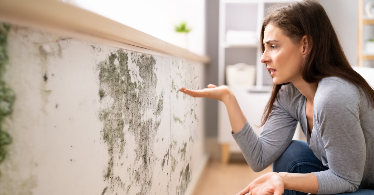 shocked woman looking at mold on wall