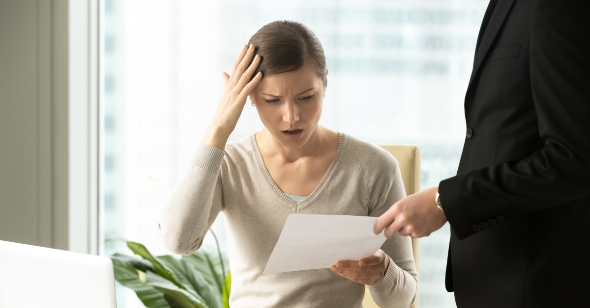 boss giving dismissal notification to confused female office worker