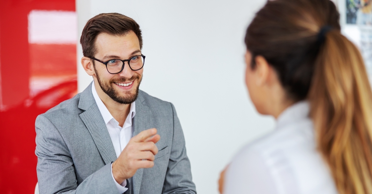 car seller sitting at the table with a woman that wants to buy a car