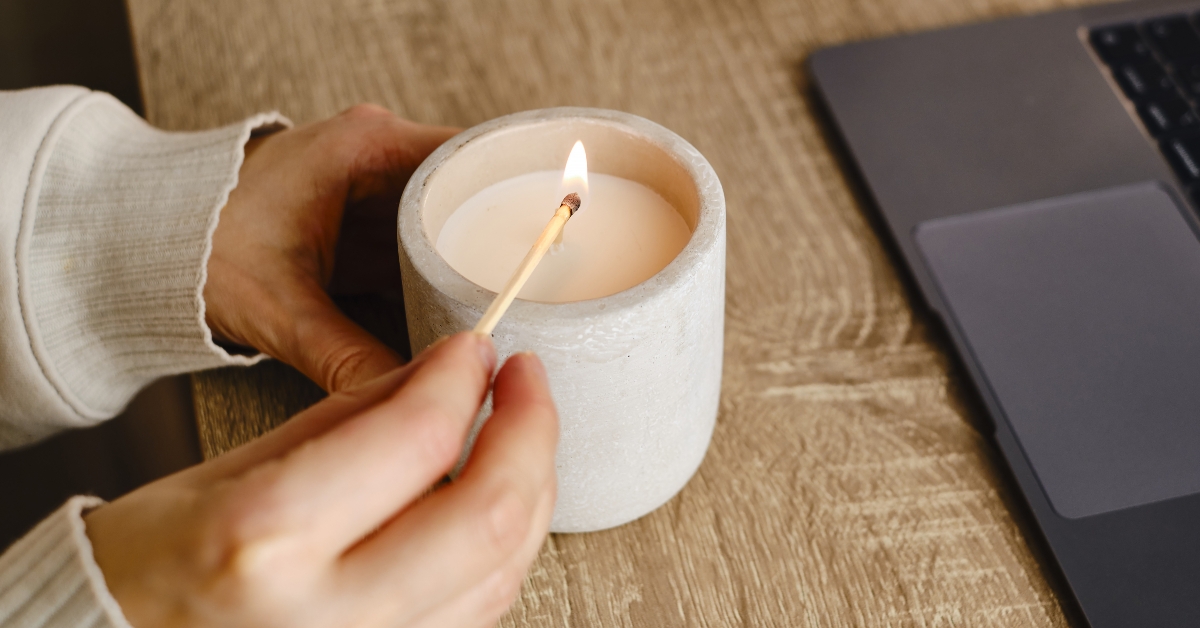 girl lights a candle at her desk at home