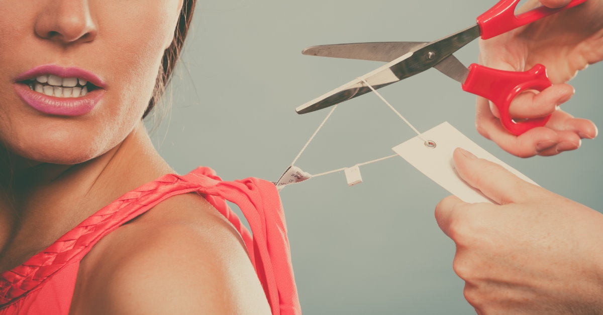 scissor cutting price tag from pink shirt woman is wearing
