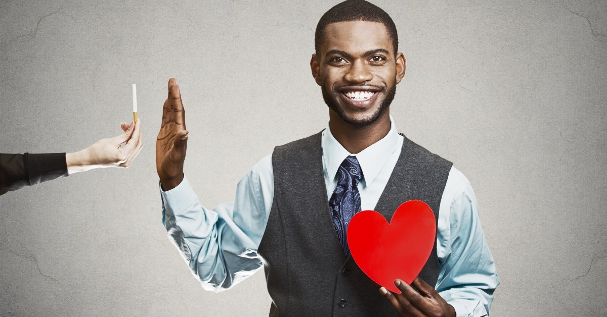 african american man standing on grey background saying no to cigarette 