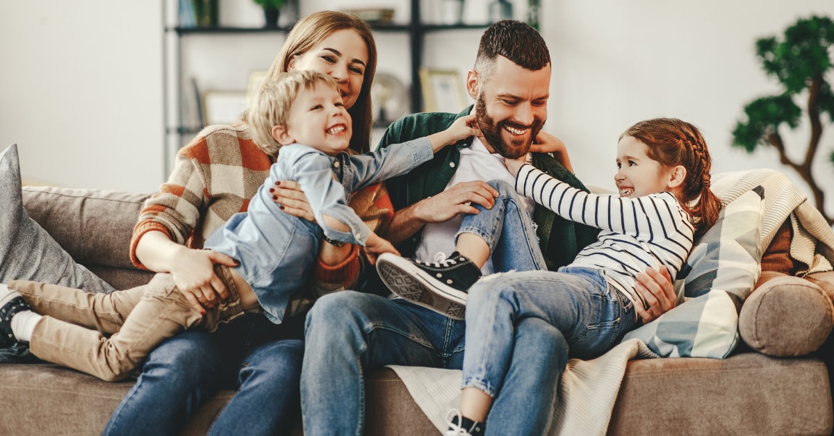 happy family sitting on couch playing with kids at home