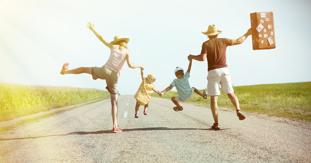 happy family out on holiday walking in the middle of sunny county road