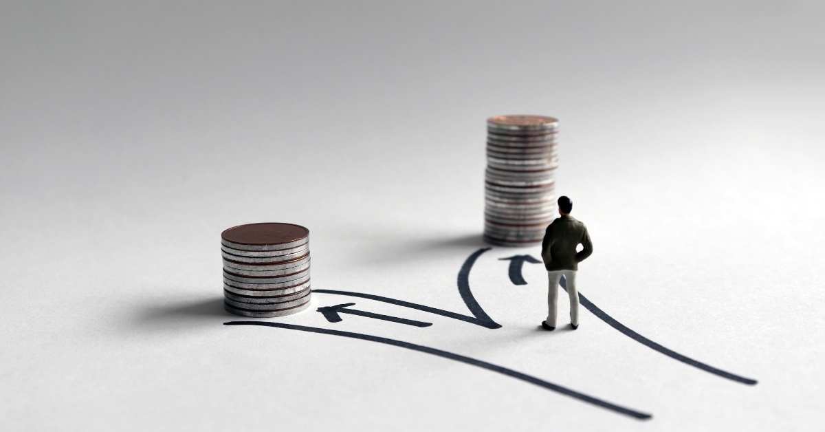 miniature man standing in front of two paths
