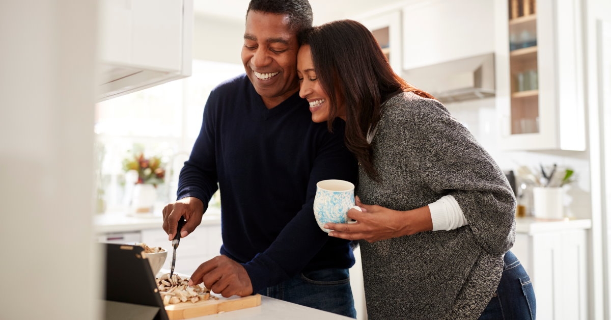 happy african american couple in kitchen cutting vegetables to prepare food