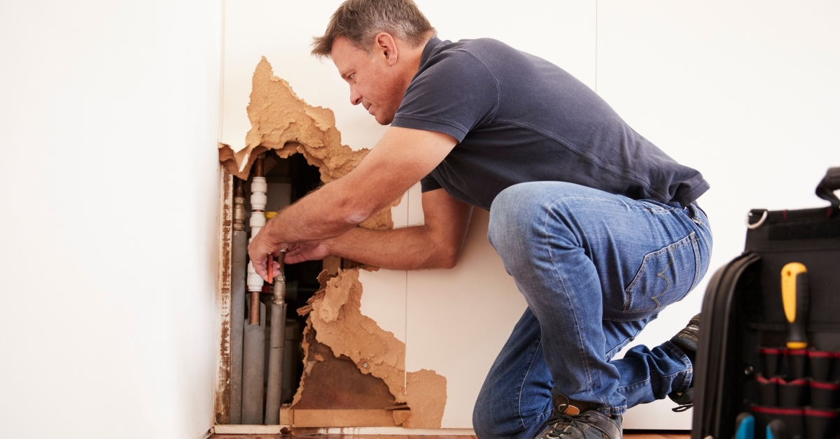 middle aged man repairing burst water pipe