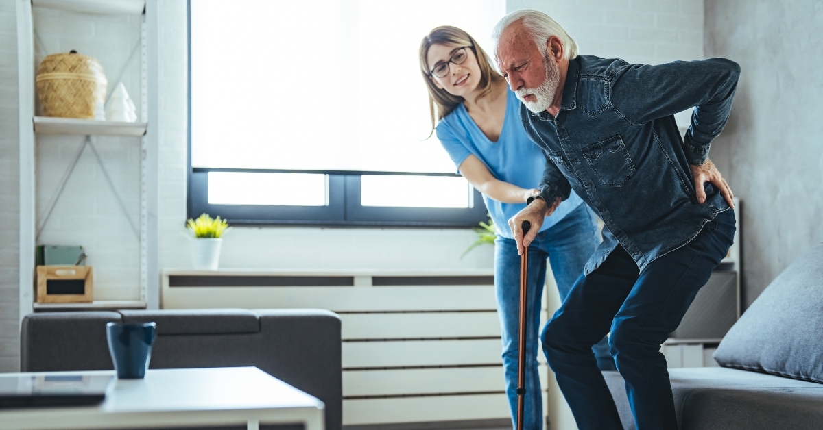 nurse assisting senior man to get up from bed