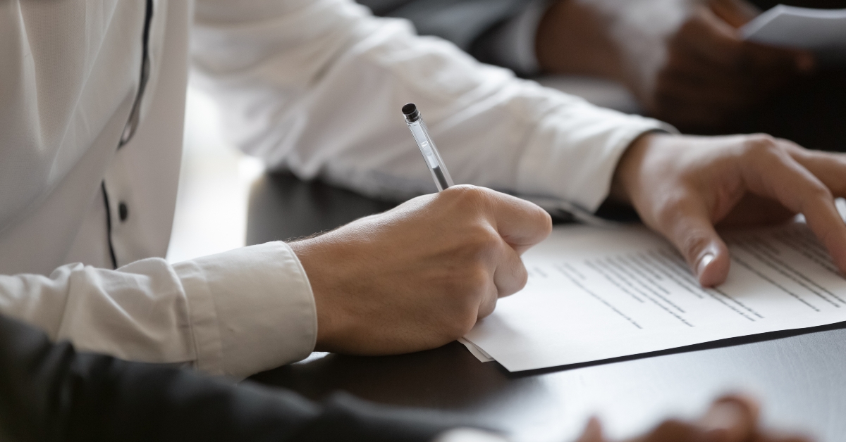 customer hands signing paper contract