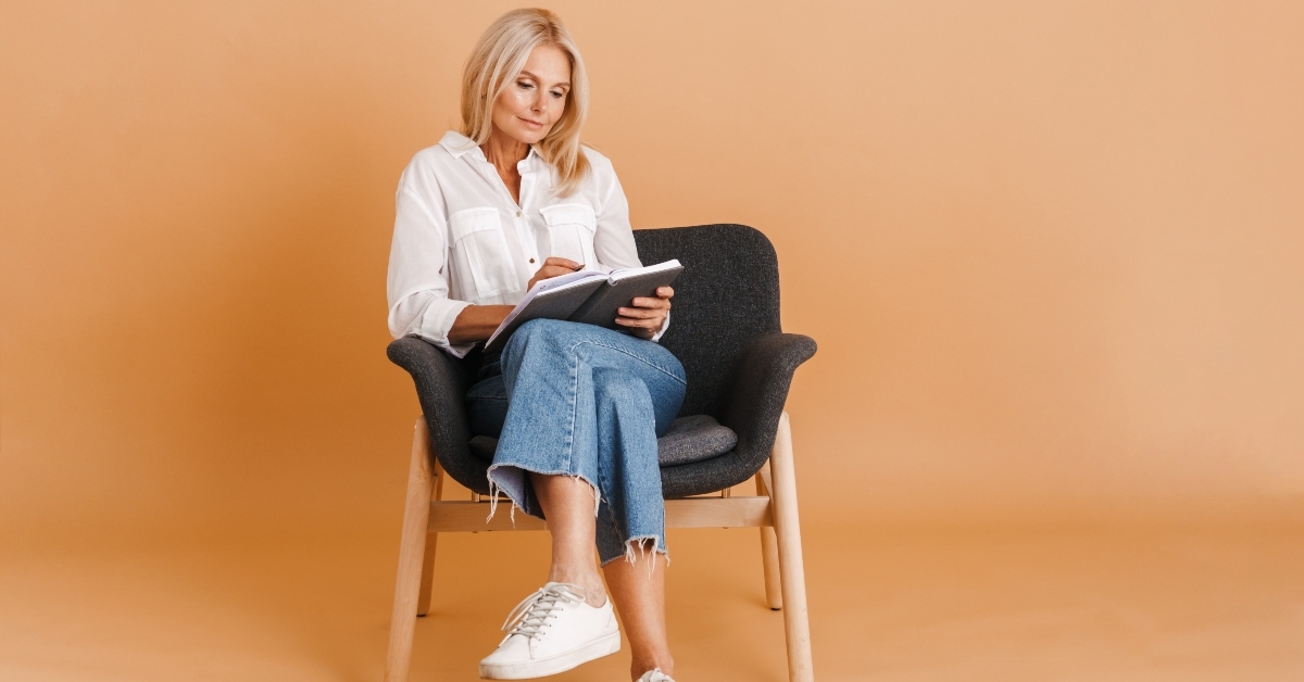 blonde woman writing down notes while sitting in chair
