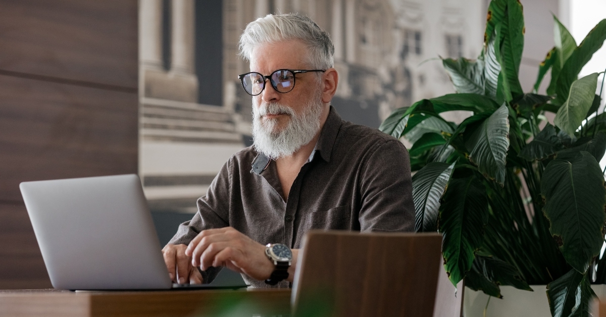 gray-haired man working with a laptop