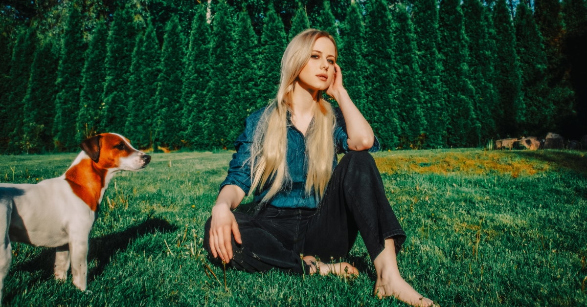beautiful blonde woman wearing denim shirt sitting on grass