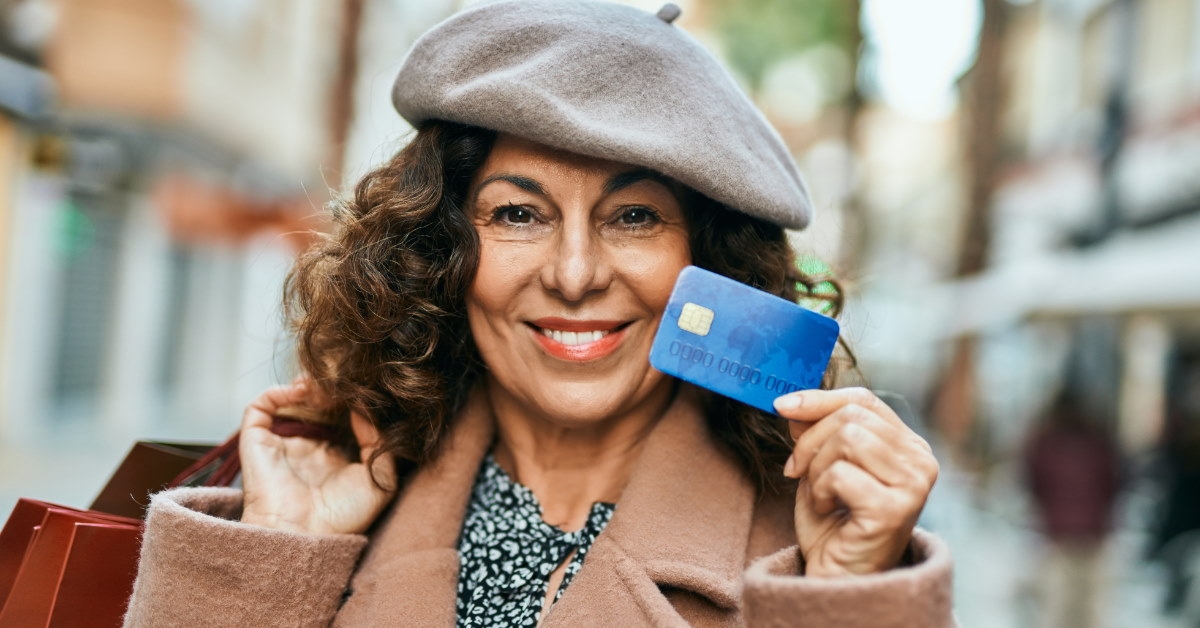 middle age woman shopping in city holding card and shopping bags