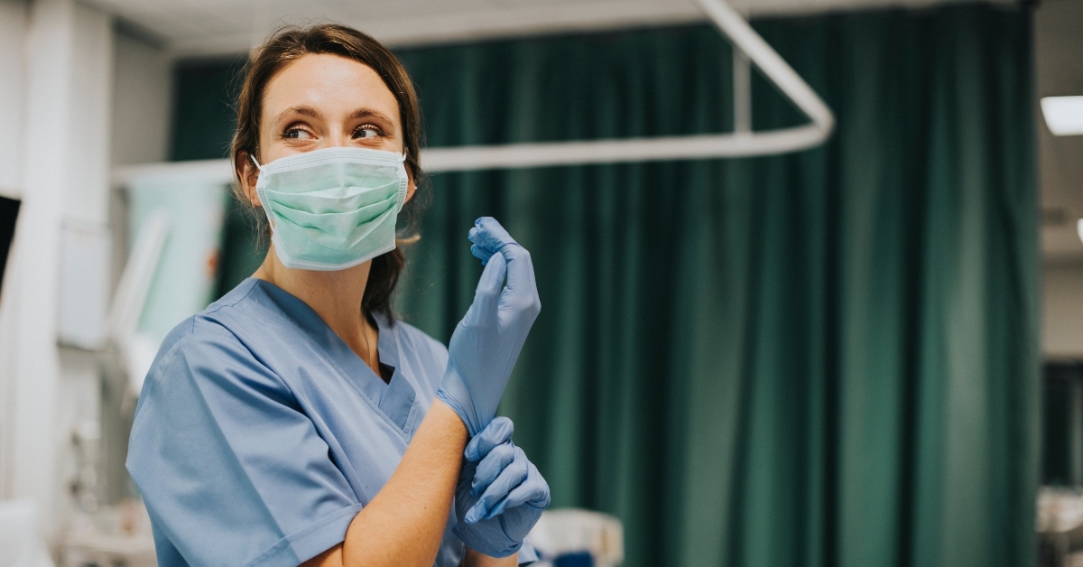 nurse putting on gloves in hospital room